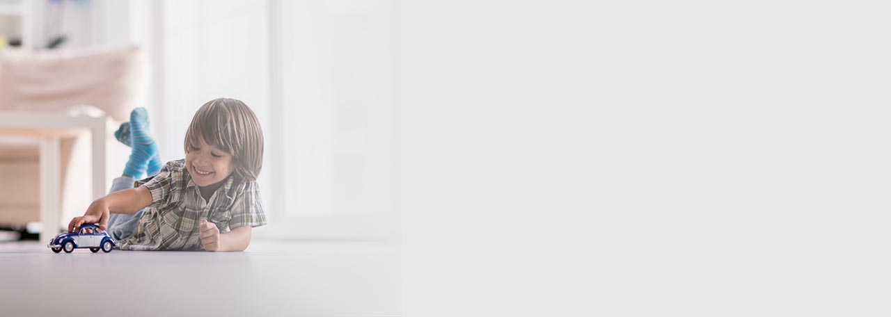 Boy playing with a toy car on the floor.