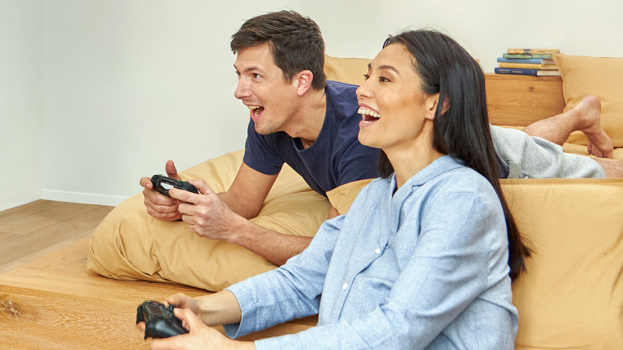 Couple laughing while playing video games in a cosy room with balanced temperature